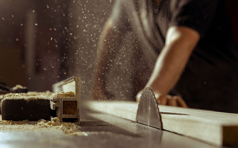 A man cuts wood on a circular saw in a joinery.