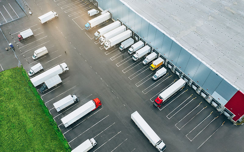 Aerial view of many trucks at the loading docks of a large distribution warehouse.
