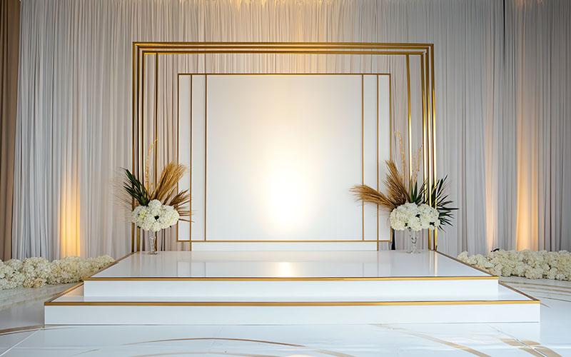 Elegant stage backdrop with gold frame and flowers, perfect for weddings and special occasions.